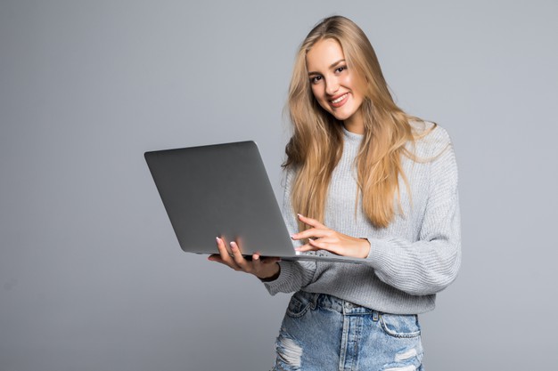 young_happy_smiling_woman_casual_clothes_holding_laptop_sending_email_her_best_friend_isolated_gray_background_231208_7443.jpg
